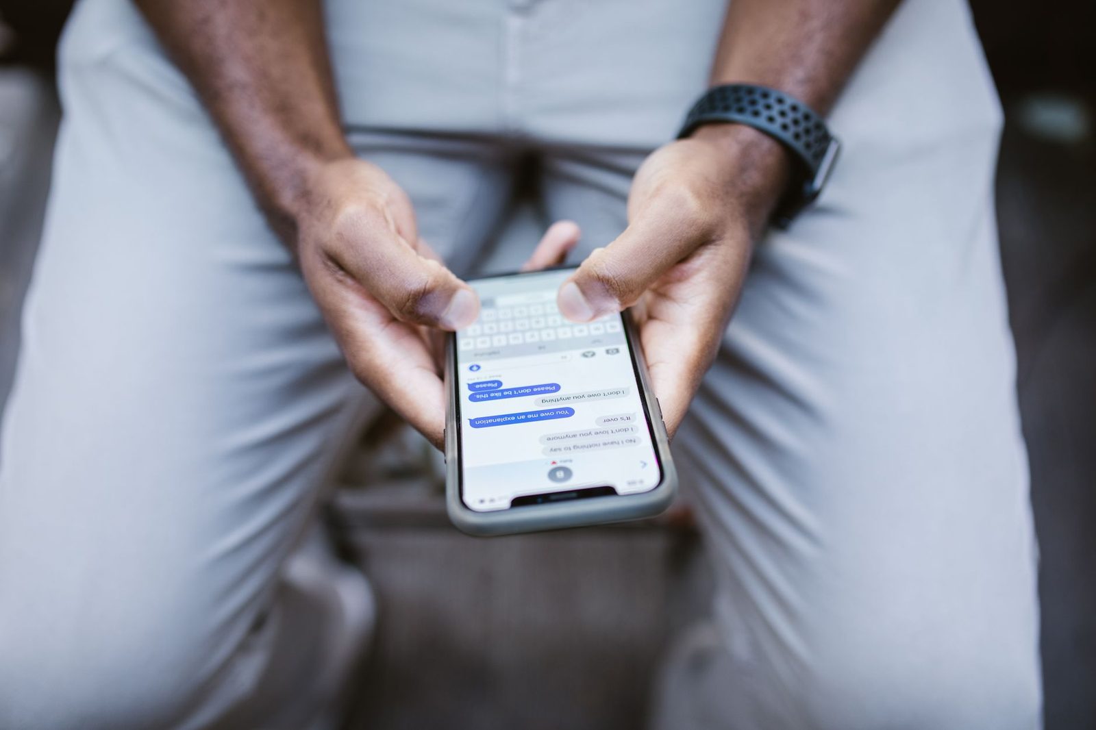 A close-up of a man typing a text message on his smartphone.