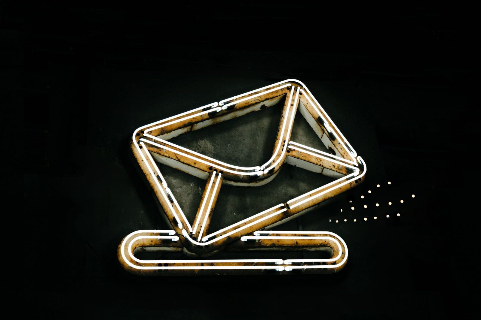 A glowing neon envelope icon on a black background, representing email communication.