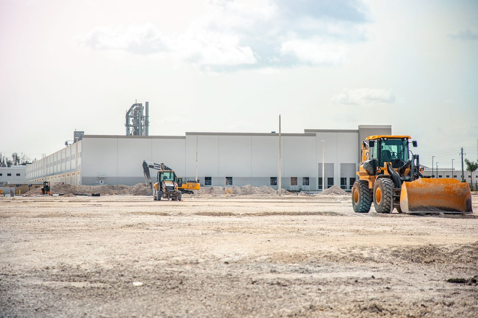 A large construction site with heavy machinery and a partially built industrial building.