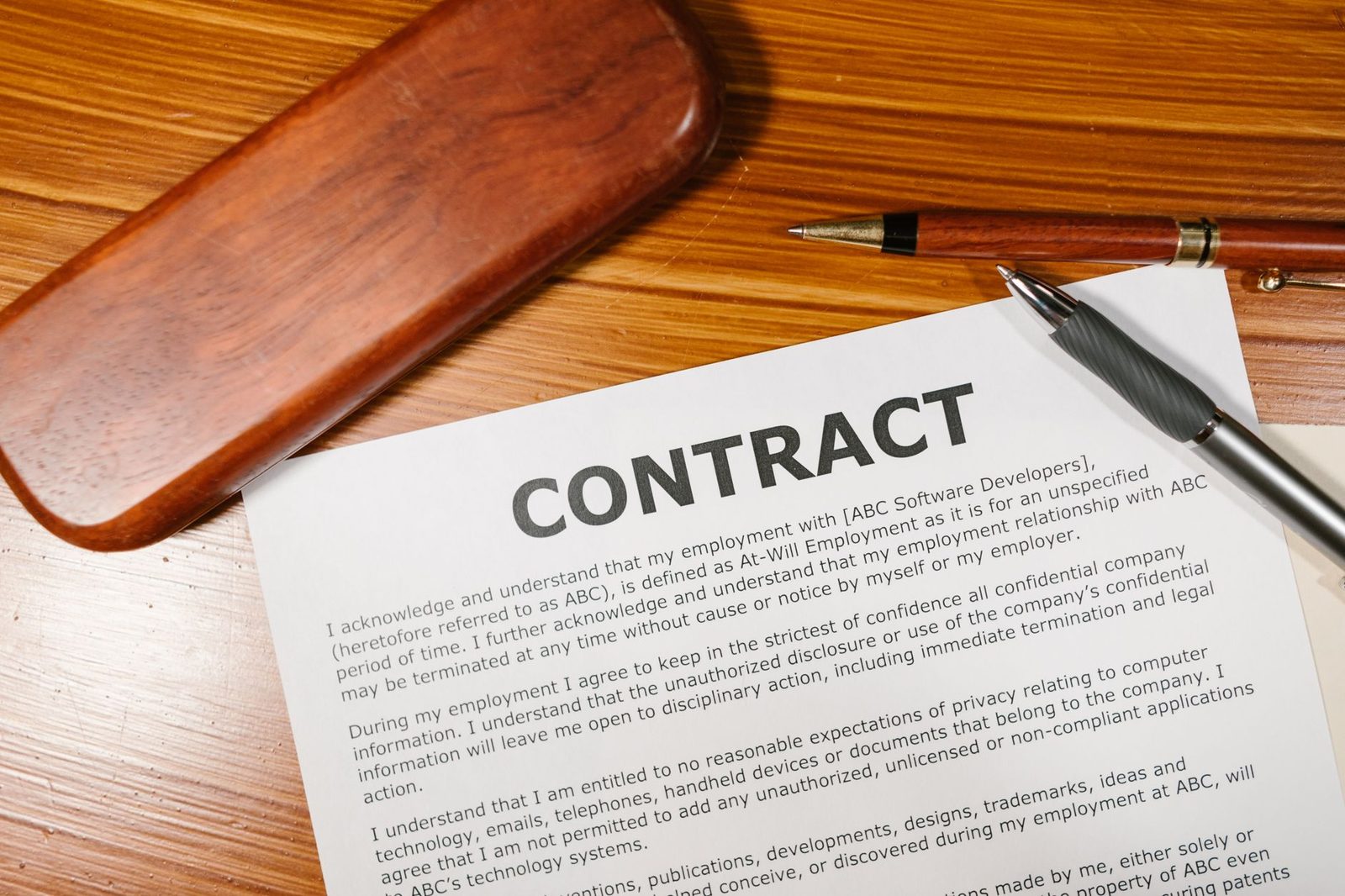 Un bolígrafo sobre un contrato impreso en un escritorio de madera.