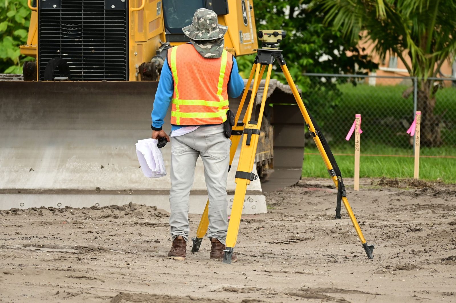 A surveyor with measuring equipment takes measurements on a construction site.