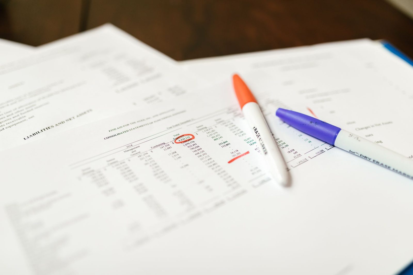 Close-up of financial documents with pens highlighting key data points on a desk.