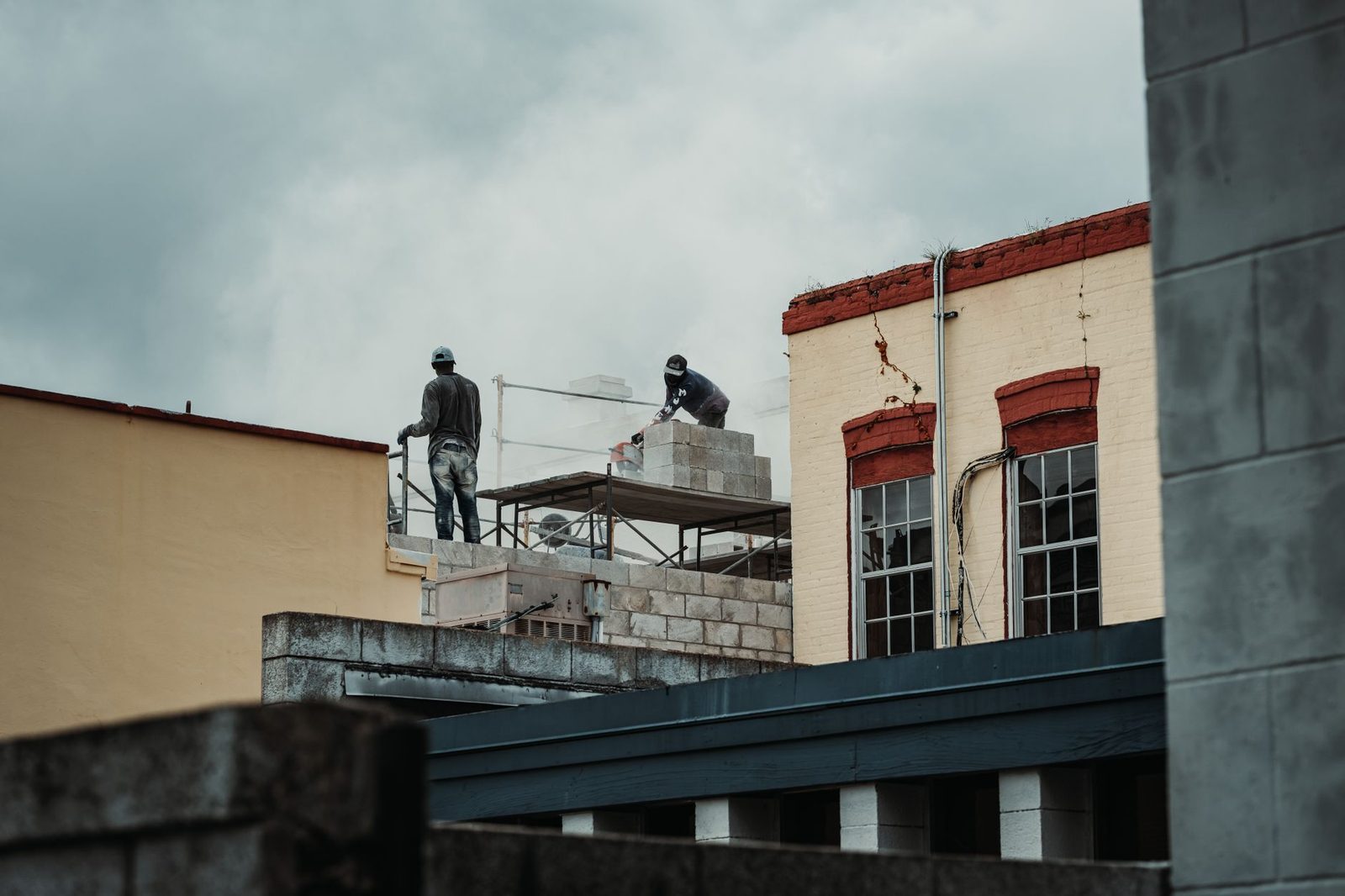 Construction workers laying bricks on a daytime building site.