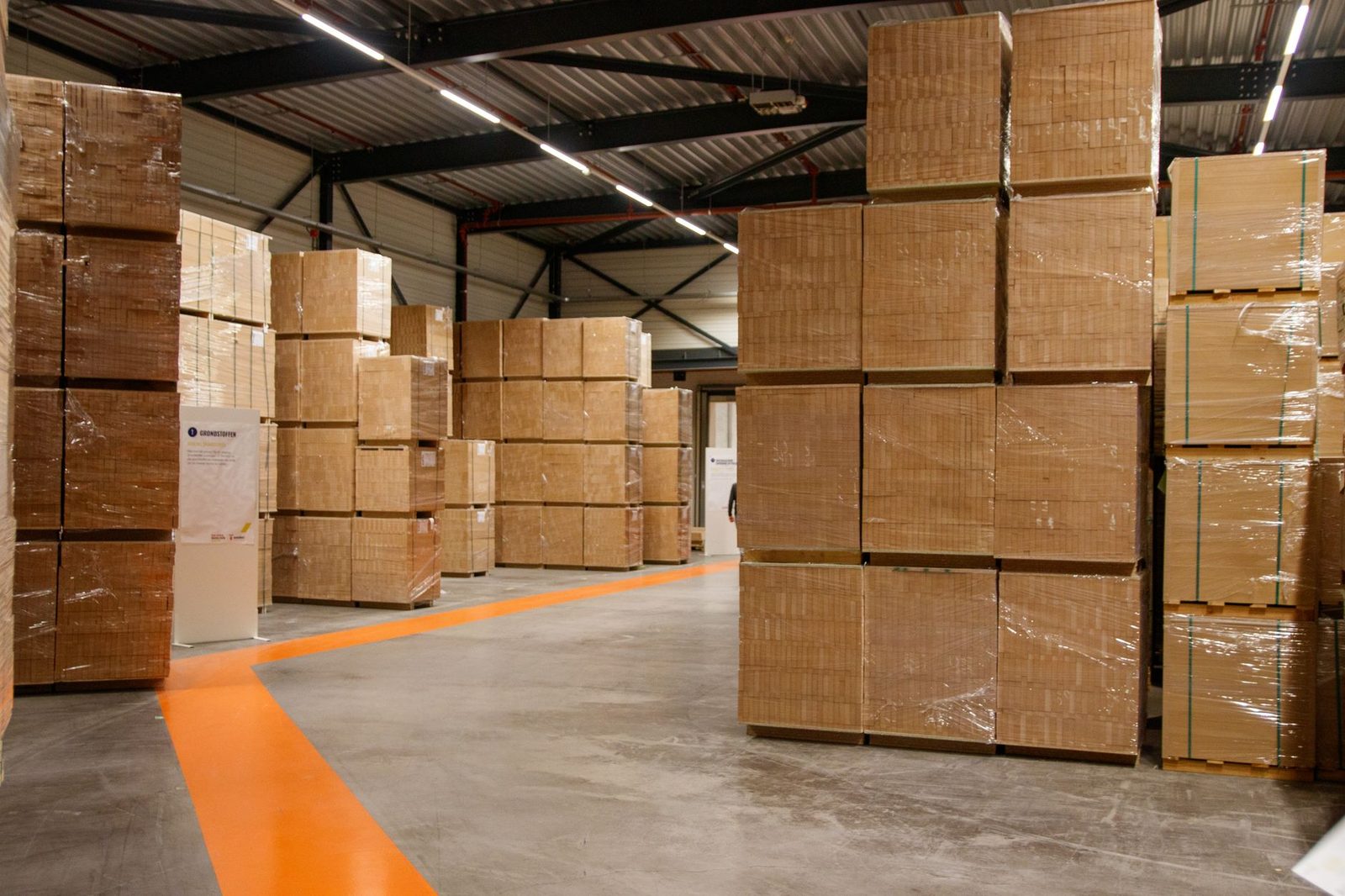 Interior amplio de un almacén con altas pilas de cajas de cartón para almacenaje y envíos.