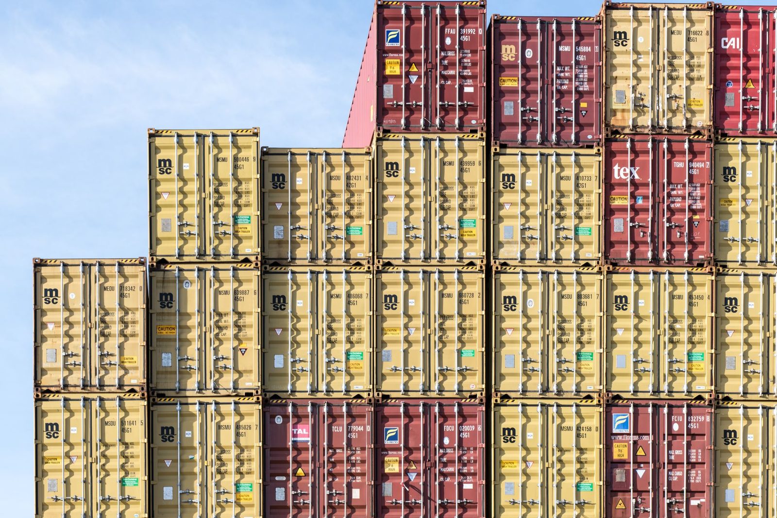 Stacked colorful shipping containers at a busy port, representing global trade and logistics.