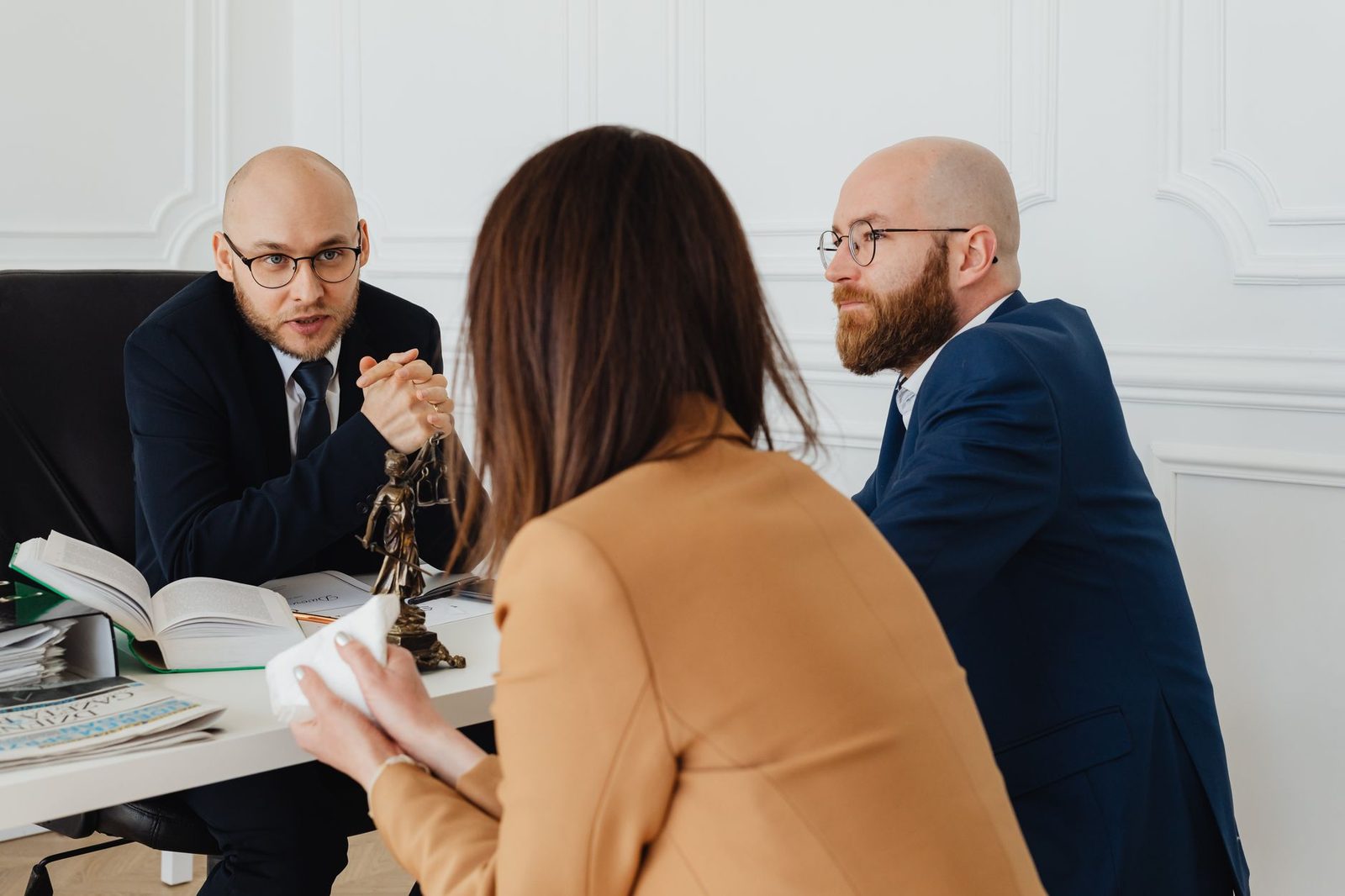 Two lawyers in a modern office discuss legal documents across a conference table.
