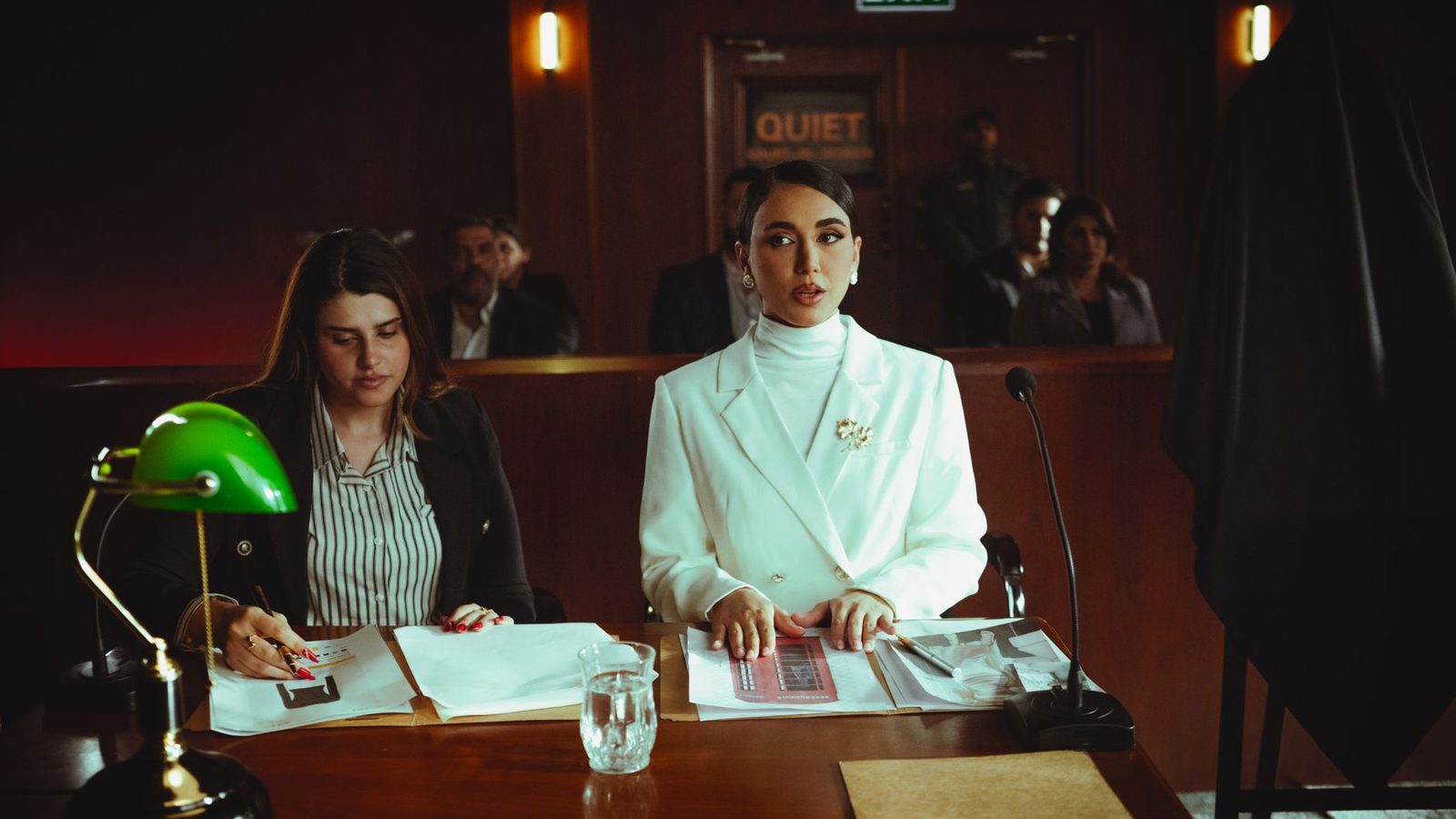 Two women lawyers review legal documents together in a courtroom.